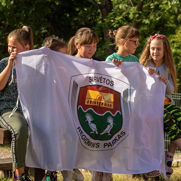 a group of children holding up the flag for the Sirvetos Regional Park in Lithuania