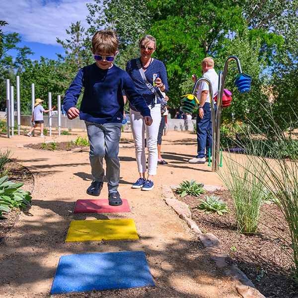 a young boy jumping on musical stepping stones of difference colours in a musical playground