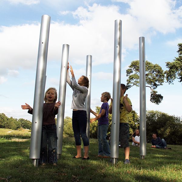 family playing on huge musical chimes in a park