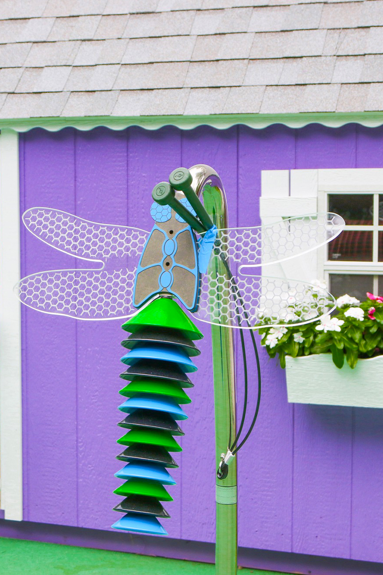 An outdoor musical instrument shaped like a Dragonfly complete with mallets and mounted on a stainless steel frame