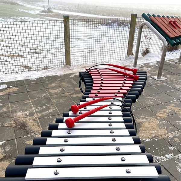 a large outdoor xylophone with silver and pink notes installed in a retirement community