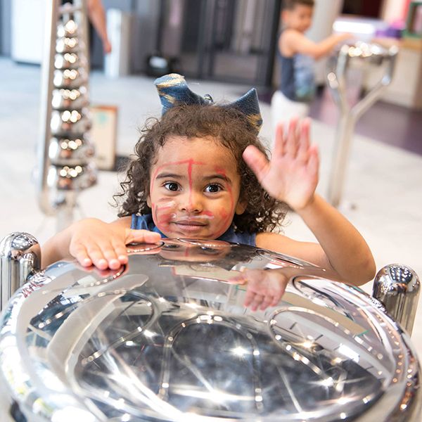 little girl playing on a stainless steel tongue drum in the minnesota children's museum