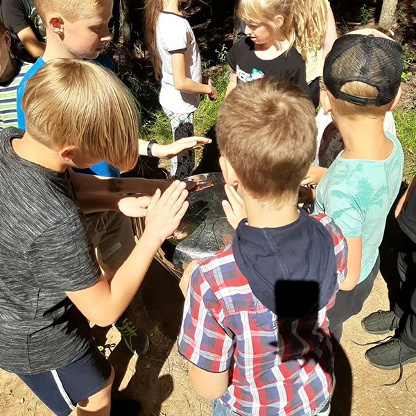 children gathered around and playing on a stainless steel outdoor tongue drum at the Sirvetos Regional Park