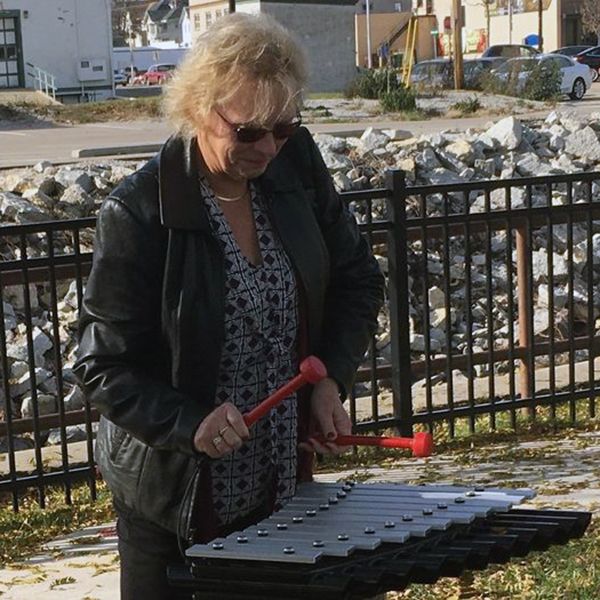 lady playing an outdoor xylophone on the beaver dam riverwalk outdoor musical instrument trail