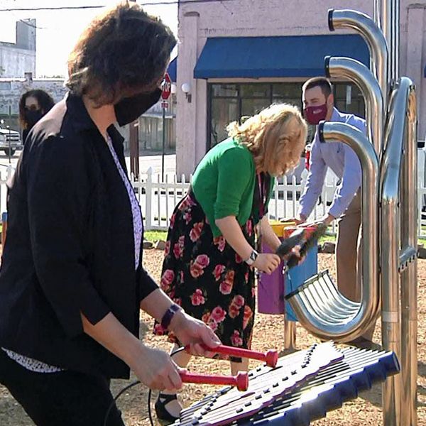 two ladies playing on the outdoor musical instruments in the Harmony Garden at Sherman Public Library