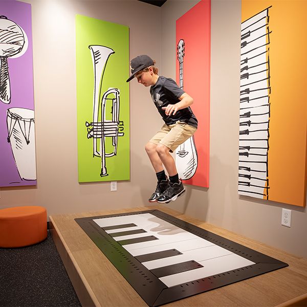 a young boy in a blue cap jumping on an interactive floor piano