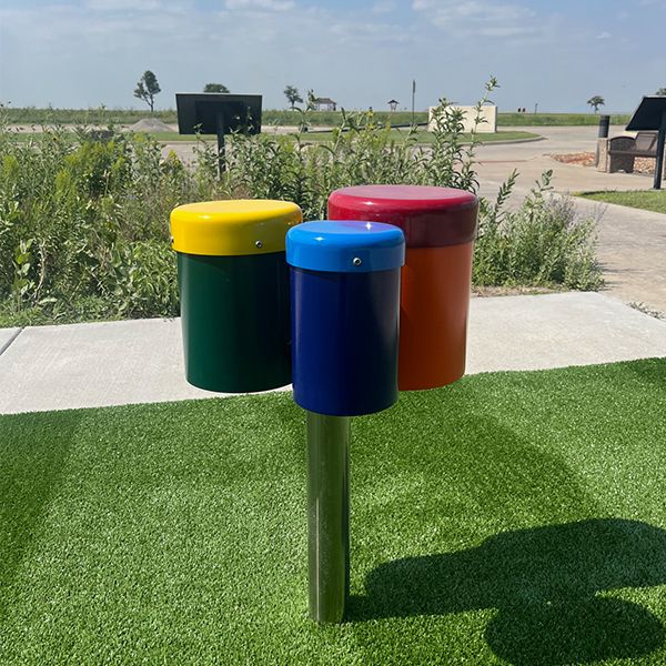 a set of outdoor drums which has a single post with three bongo drums attached each in different colors and sizes