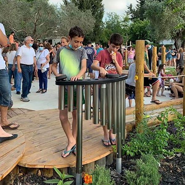 two boys playing a piped outdoor musical instrument in the Kibbutz Magal musical memorial playground