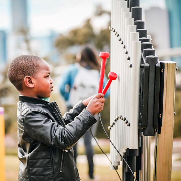 Young boy playing on an outdoor cherub xylophone at the Leonel Castillo Community Center 