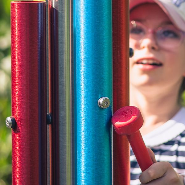 a close up of a young girl wearing glasses playing a set of bright colored chimes