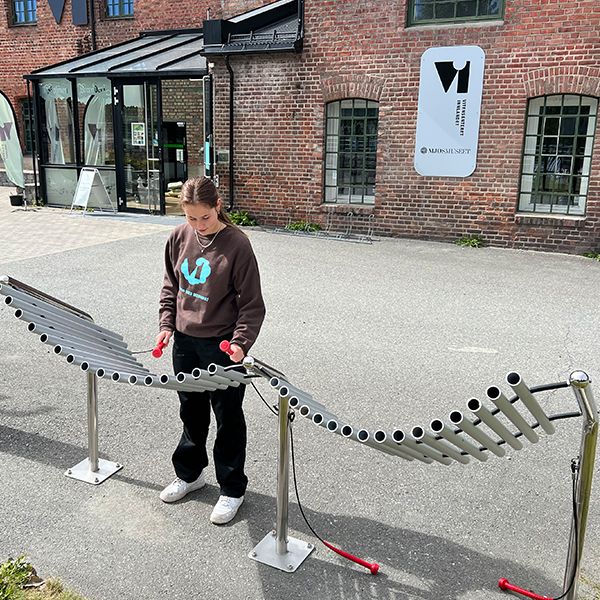 female teenager playing an outdoor musical instrument outside the Vitensenteret Innlandet Science Centre in Norway