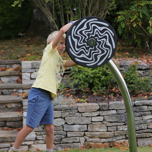 young blonde boy spinning a large black and silver rainwheel