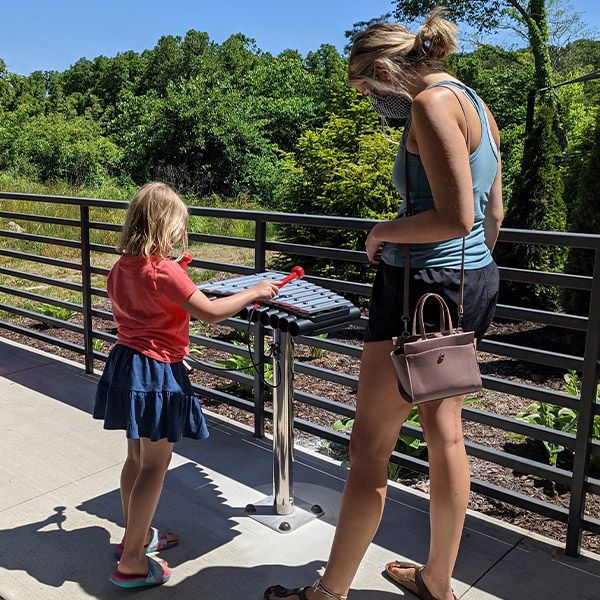 a young blonde girl playing an outdoor xylophone on the patio of the Scenic Regional Library