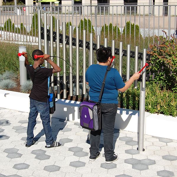 Two young men playing on the silver outdoor musical chimes on the plaza outside White Plains Public Library NY