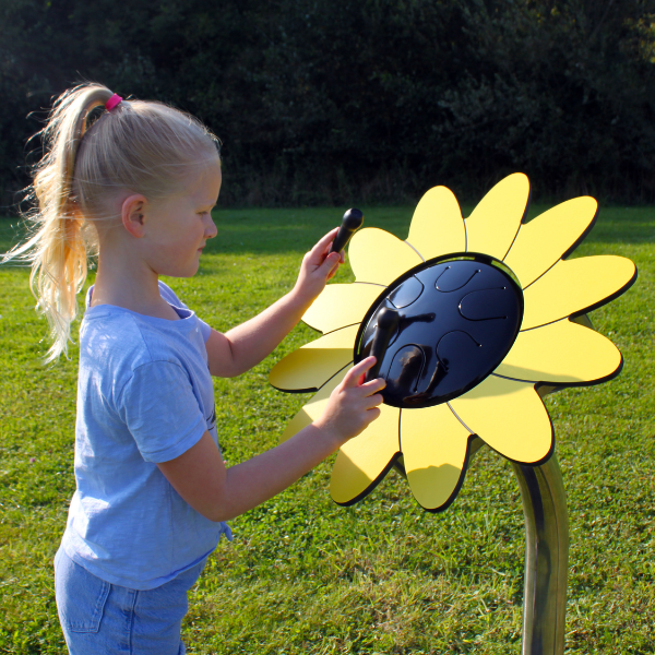 image of a young girl playing an outdoor drum shaped like a sunflower in a library garden