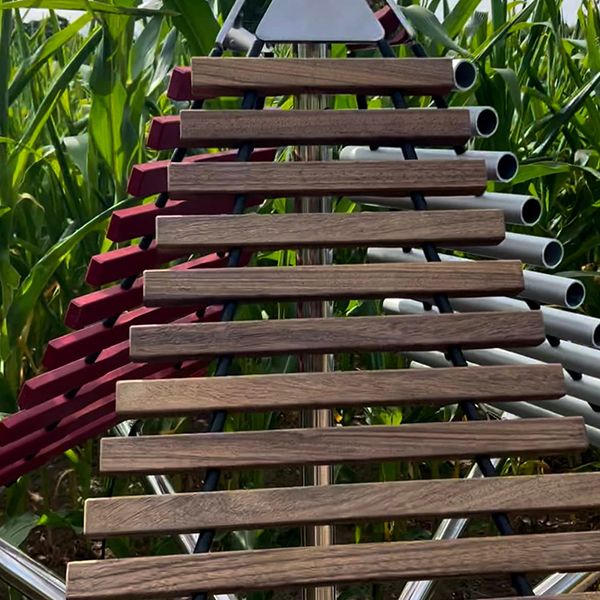 upright outdoor xylophone with three sides each of differing materials in a corn field