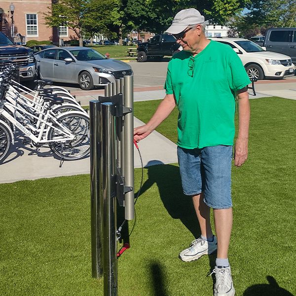 an older man playing a set of outdoor musical chimes at the town of versailles outdoor music garden