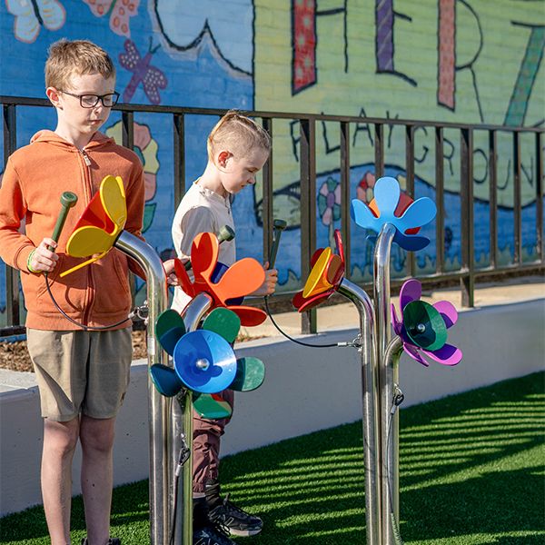 Two boys playing outdoor musical instruments shaped like large flowers in McLaren Park