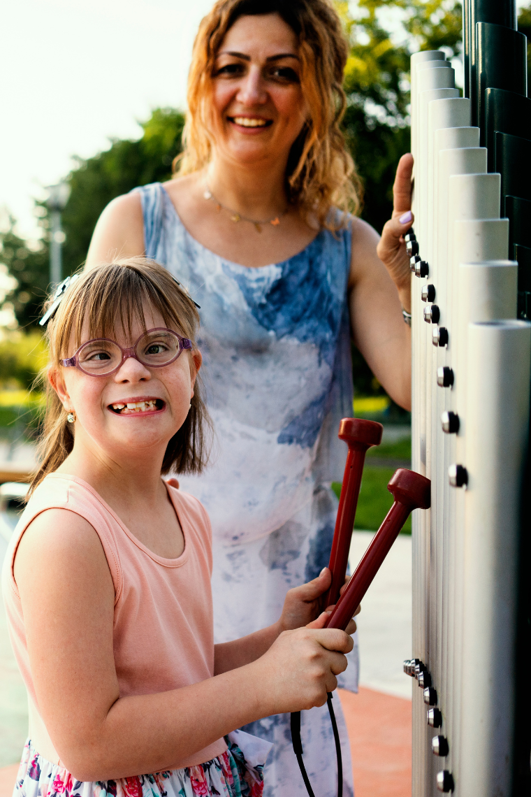 Young girl with additional needs  playing a large outdoor musical instrument in a school playground