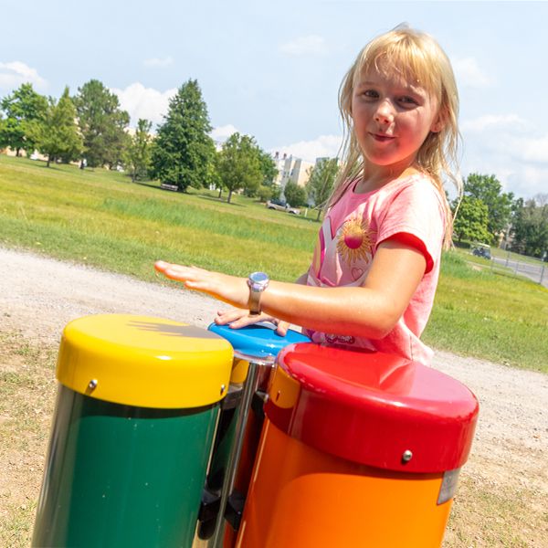 a young blonde girl playing colorful outdoor bongo drums