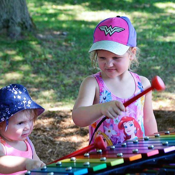 two young girls playing a rainbow coloured outdoor xylophone in the belleville rotary music garden