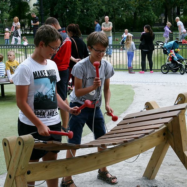 two young men playing large timber marimba xylophone is busy park