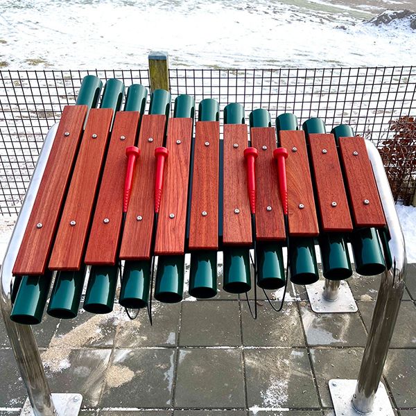 a large wooden outdoor marimba with green resonators at a retirement community garden