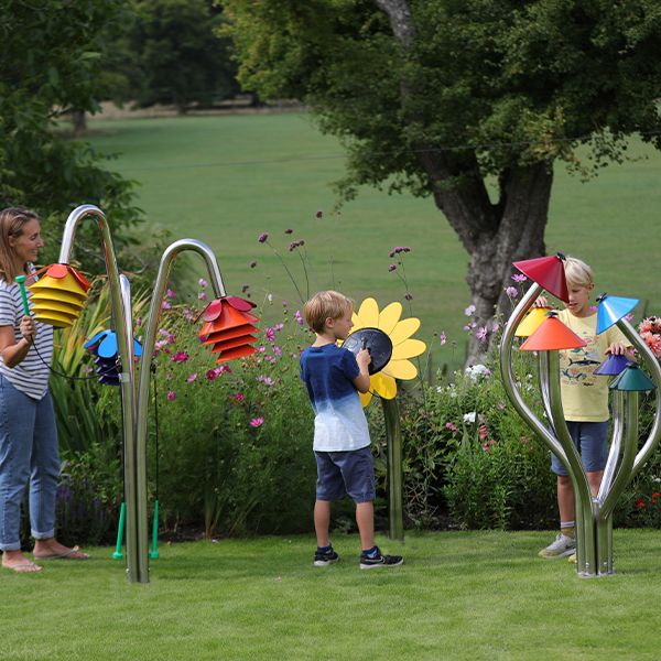 three outdoor musical instruments inspired by nature being played by a mother and two sons