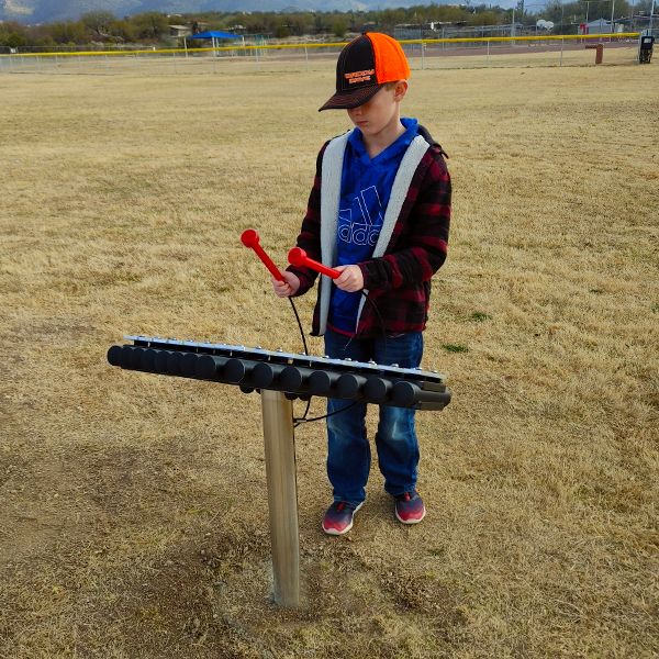 pupil from Tanque Verde School playing a large outdoor musical instrument in the new outdoor music classroom