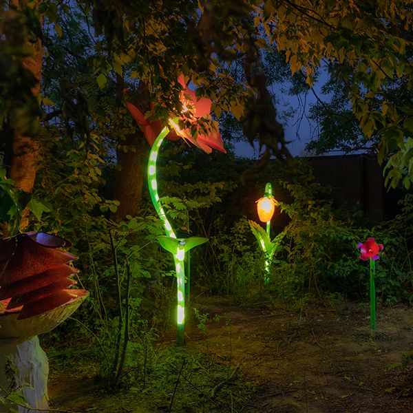 outdoor musical flowers and flower sculptures lit up at night in a sculpture garden