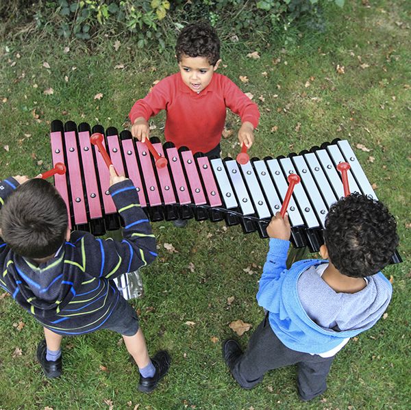 birds eye view of three boys playing a large outdoor xylophone in a park