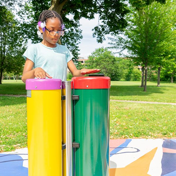 a young girl playing colorful outdoor drums in a music park