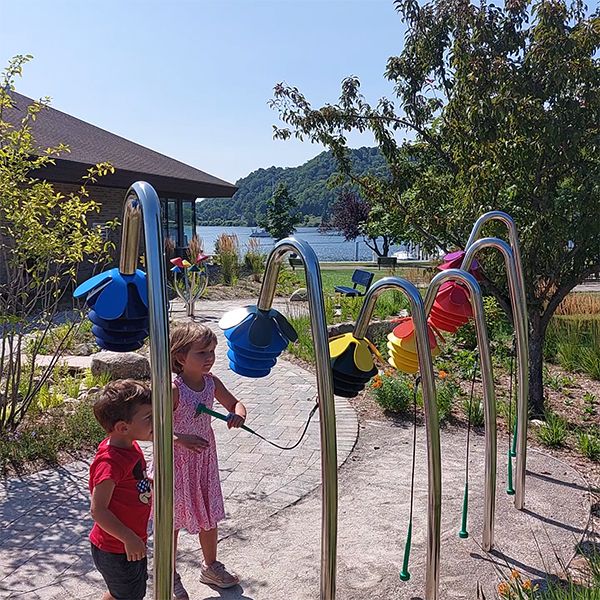 two small children playing on a row of outdoor musical instruments shaped like flowers outside Benzies Shore Library