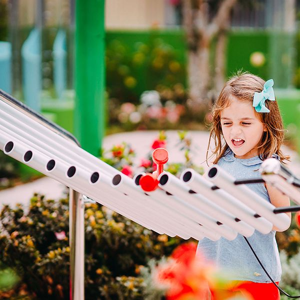 a young girl playing a giant outdoor xylophone in a play park