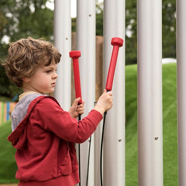 Young boy playing large tubular bells in Denzils Music Mayhem Outdoor Musical Park at West Midlands Safari Park