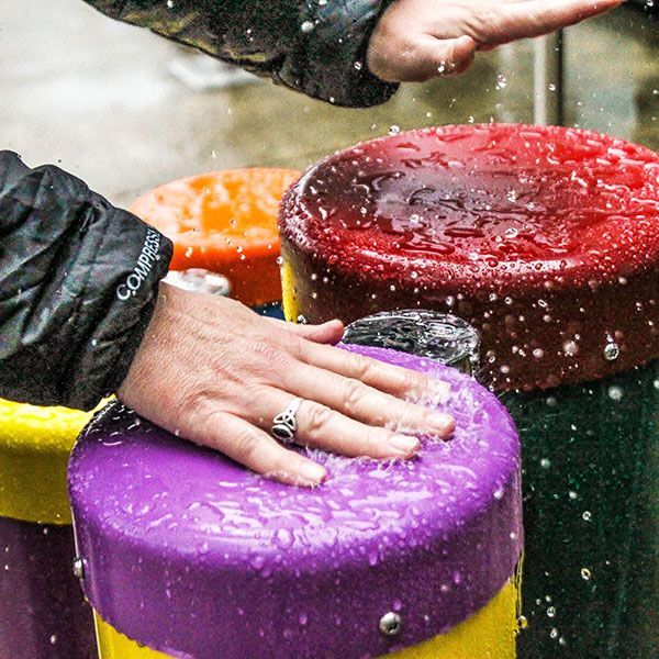 hands hitting a colourful drum top in the rain