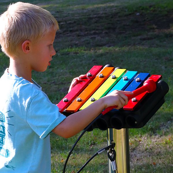 rainbow colored metallophone being played by a young blond boy