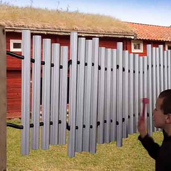 Young boy playing musical chimes with a farm scene in background