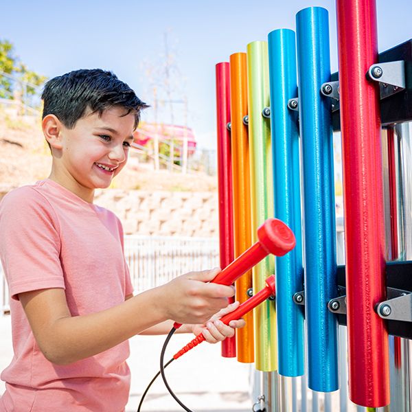 young boy playing rainbow colored musical chimes in the sesame street music park in seaworld