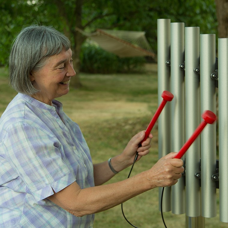 Image of older lady playing silver musical chimes