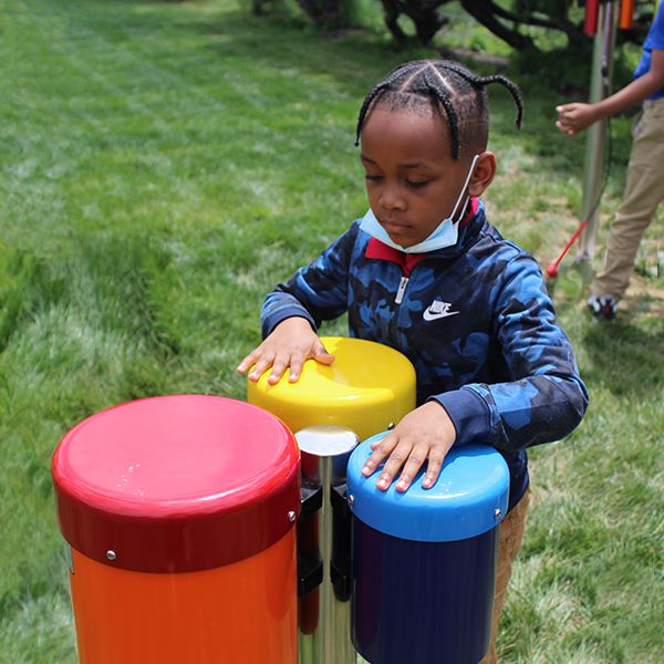 School child playing colorful outdoor conga drums at the Lift for Life Academy