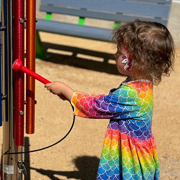 a young girl playing a musical chime post in a musical playground