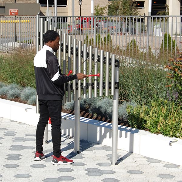 Young man playing on the silver outdoor musical chimes on the plaza outside White Plains Public Library NY