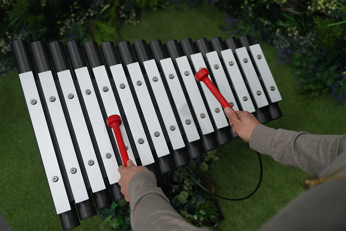 close up image of an outdoor xylophone being played with red mallets