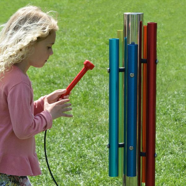 a young blonde girl playing an outdoor musical chime instrument