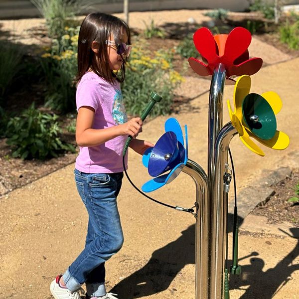 a young girl playing an outdoor musical instrument shaped like a bunch of flowers