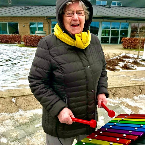 a senior lady playing a rainbow colored outdoor xylophone from Percussion Play