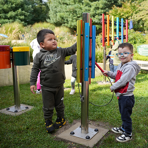 Two young boys playing an outdoor musical chime in a sensory garden