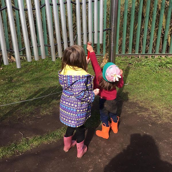 Little children playing musical chimes in a farm playground