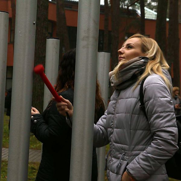 lady playing a large musical chime in a city park